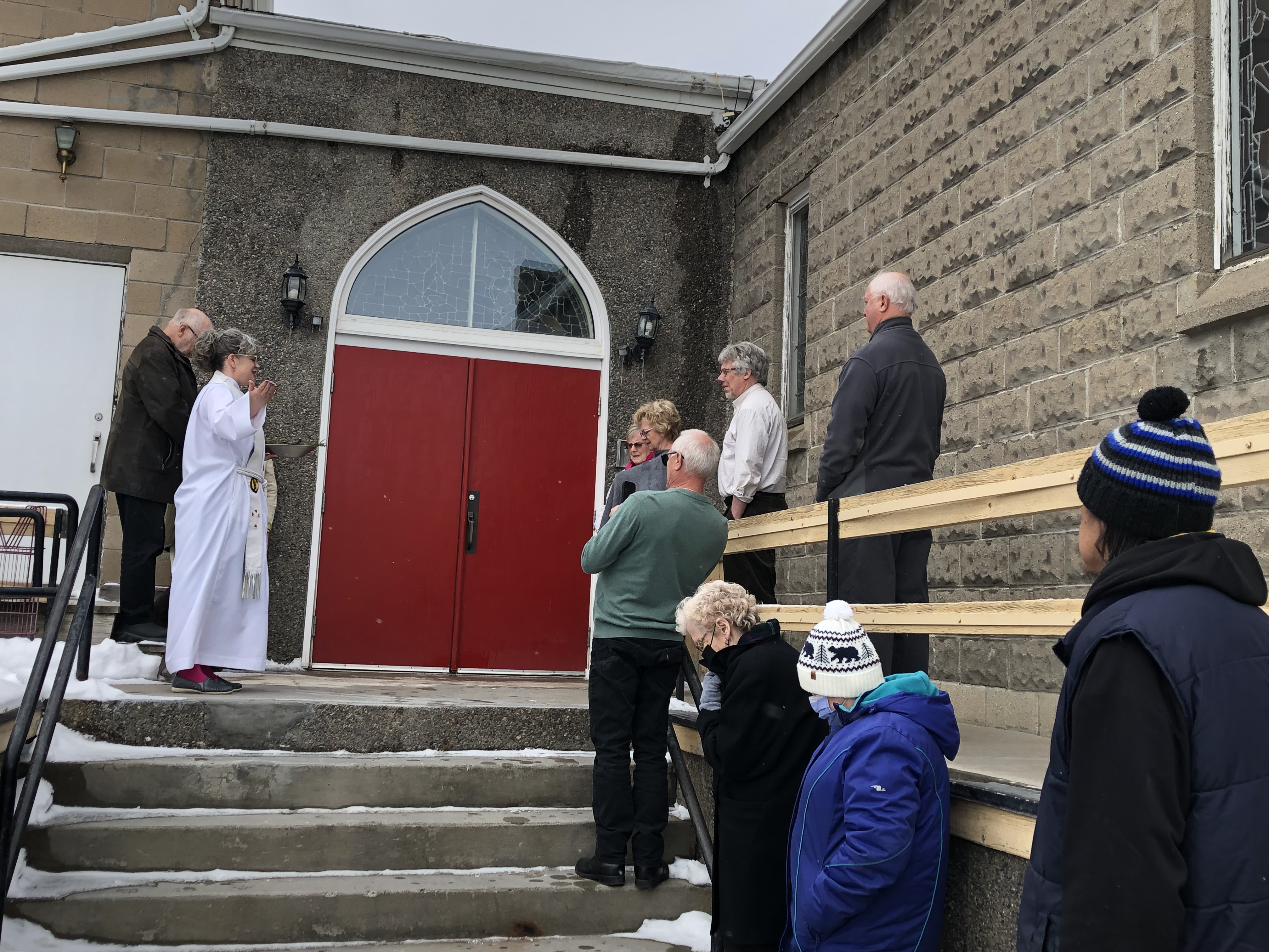 On Easter Day at St. Peter and St. James, Flin Flon, the Ven. Dr. Kara Mandryk blessed the new red doors of the church. These doors are a sign to the com- munity of the church's commitment to provide sanctuary for all who seek it. Photo Credit: Shelley Andres